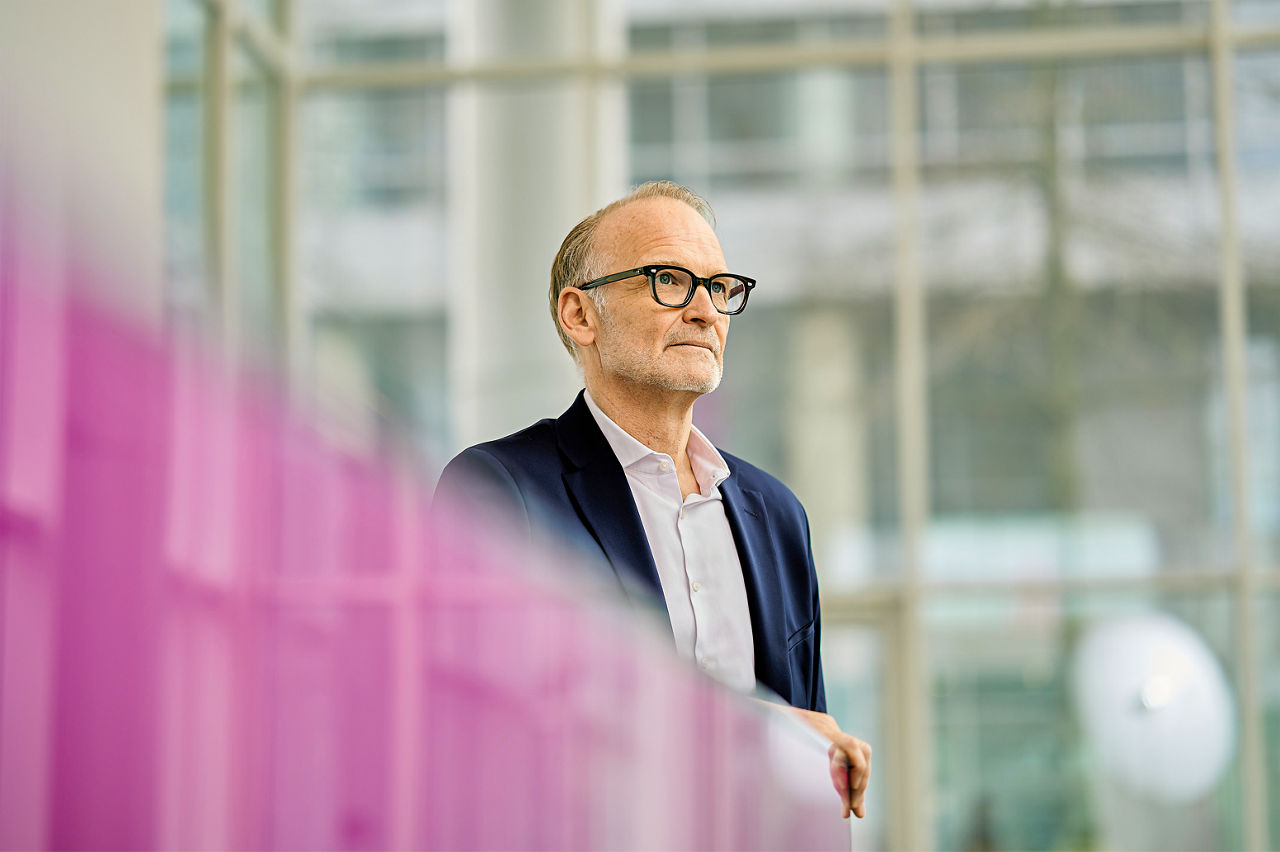 Ralf Düssel an einem purpurfarbenen Stehpult.