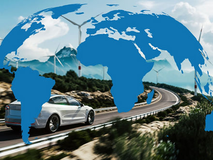 Electric car driving on country road in front of wind turbines, with the continents depicted as blue silhouettes.