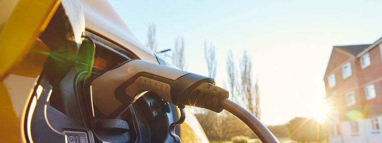 Electric car EV plugged in outside house clean energy