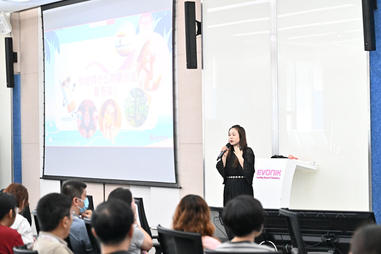 A speaker presents at an Evonik event, engaging an audience with a slide on effective prevention methods.