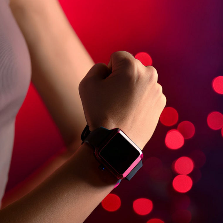 Der rechte Unterarm einer Sportlerin mit einer Smartwatch for rötlichem Hintergrund.