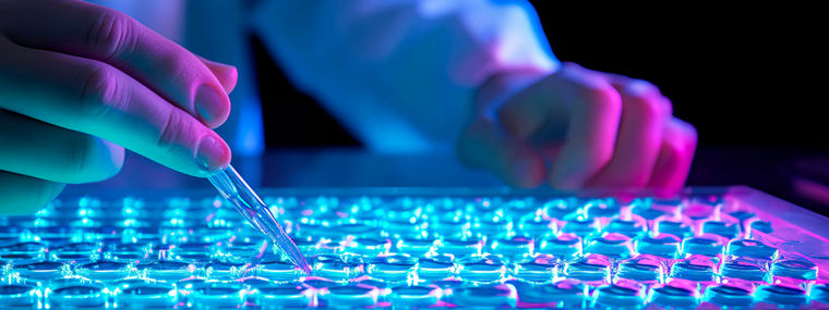 researcher's hands holding a pipette tip just above a microplate well, ready to dispense a small sample for analysis.