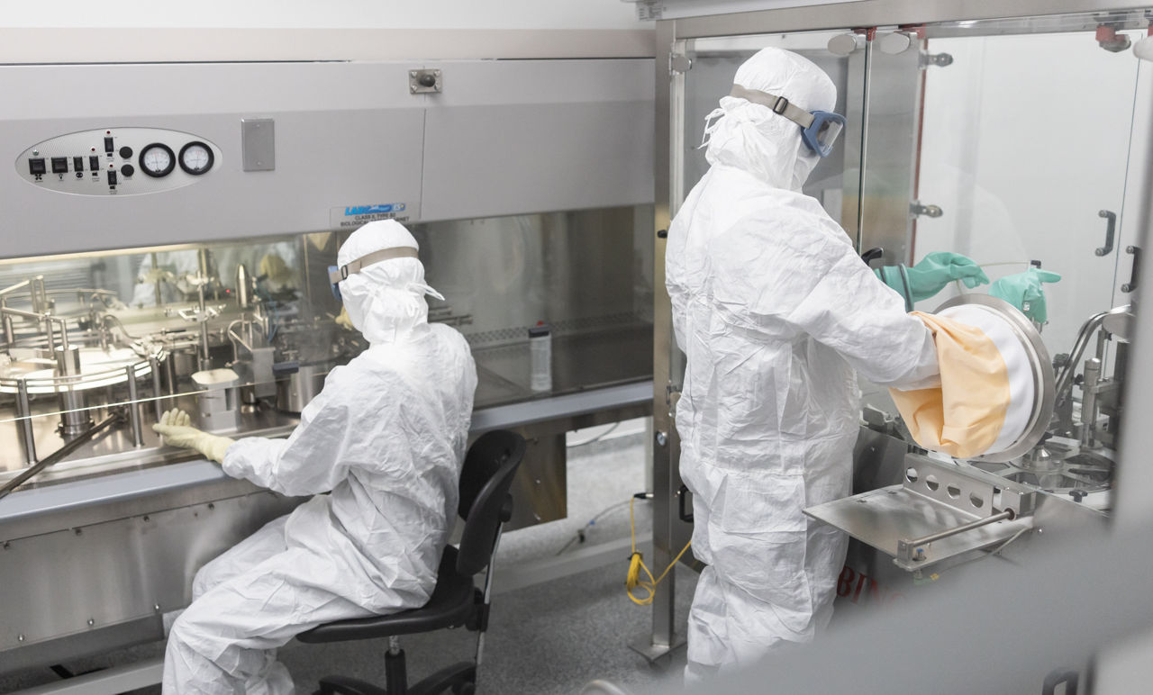 Zwei Evonik-Mitarbeiter in Vollschutzanzügen an zwei großen, metallischen Schränken.