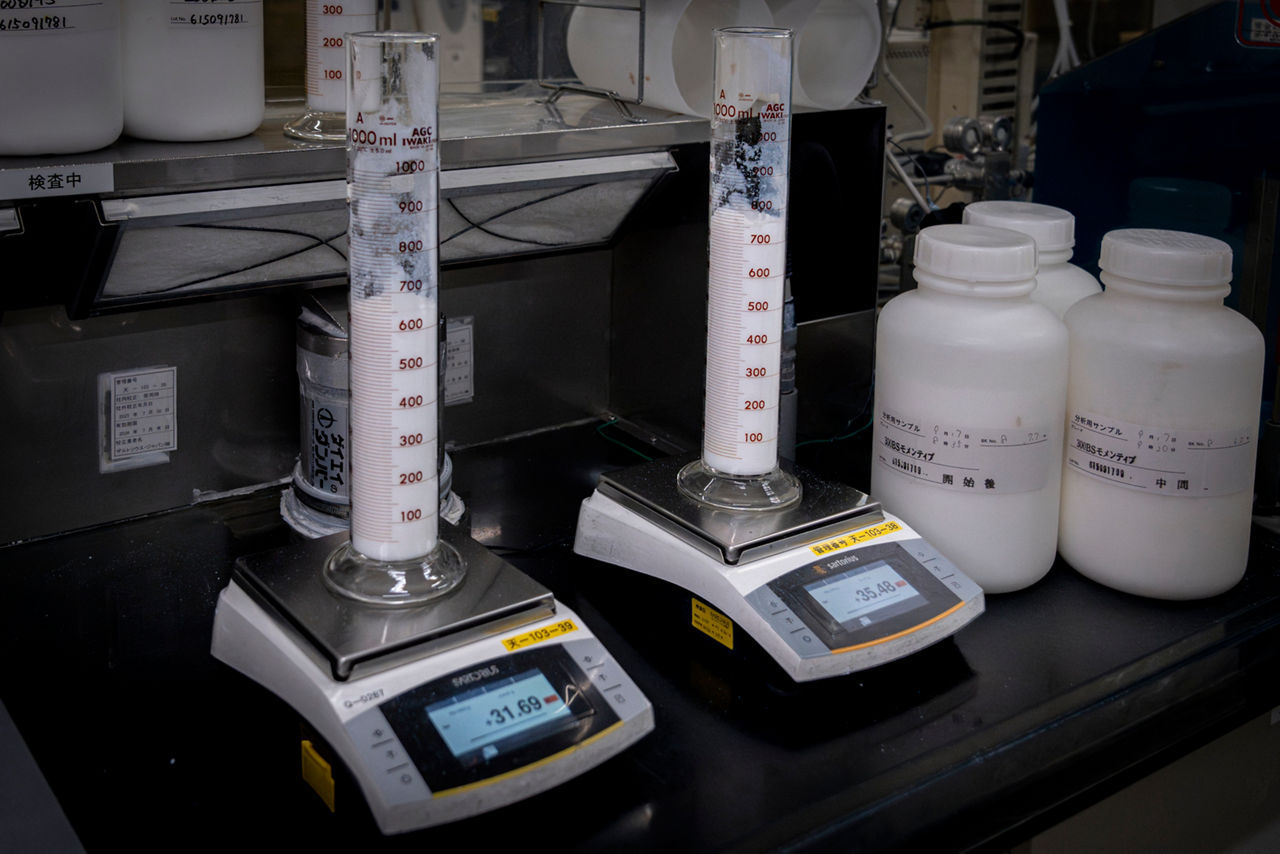 Weißes Pulver in zwei Messbehältern stehen auf elektronischen Waagen.