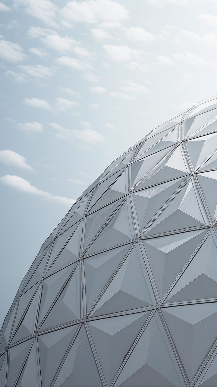 Geodesic dome structure with triangular panels under a partly cloudy sky.