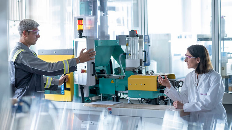 In this image, two professionals collaborate in a modern manufacturing facility, discussing machinery operations. This interaction emphasizes teamwork and communication, showcasing the importance of collaboration in enhancing process technologies within the chemical manufacturing sector at Evonik.