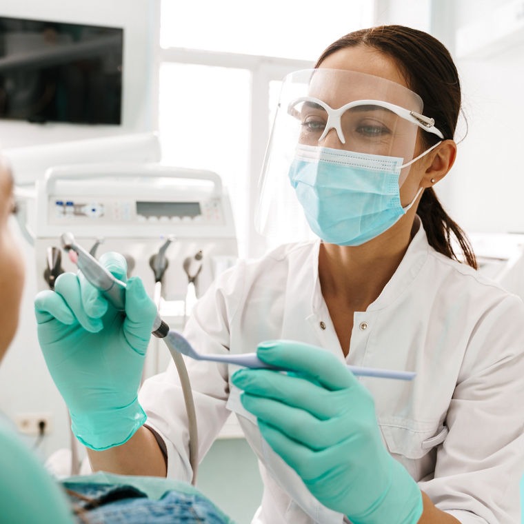 European mid dentist woman in face mask working in dental clinic