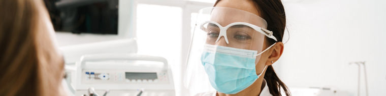 European mid dentist woman in face mask working in dental clinic