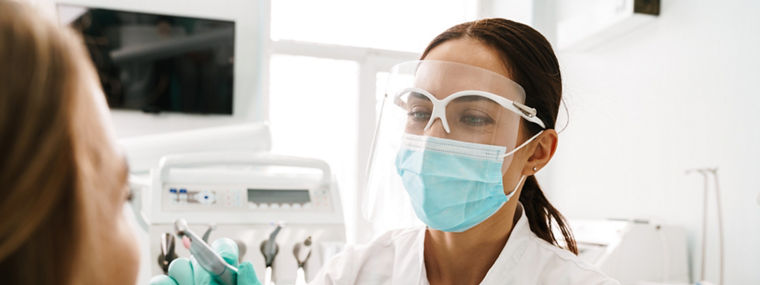 European mid dentist woman in face mask working in dental clinic