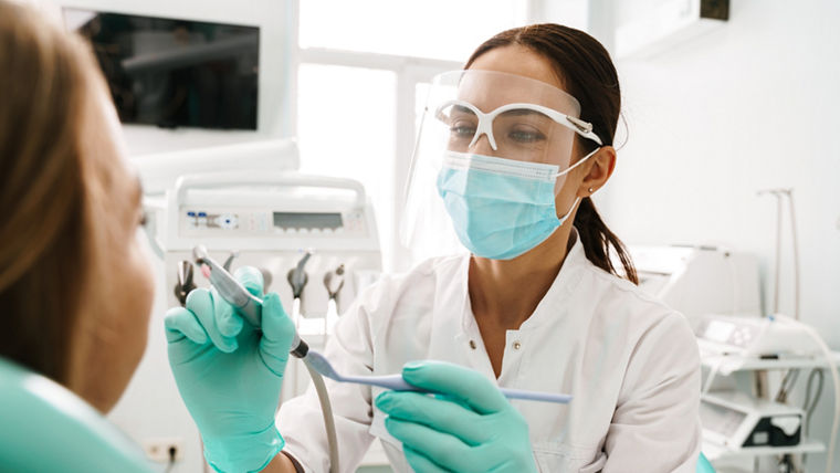 European mid dentist woman in face mask working in dental clinic