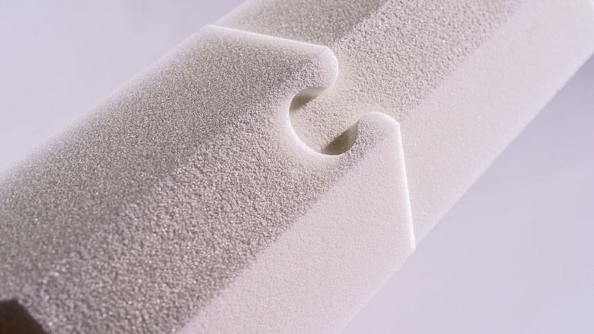 Close-up of a textured, interlocking foam piece with a curved notch for connection.
