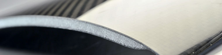 Close-up of a lightweight carbon fiber composite panel with a foam core, showing its layered structure and glossy surface finish.