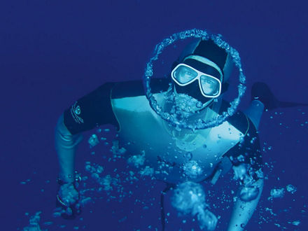 Herbert Nitsch taucht und blickt in die Kamera. Um sein Gesicht ist eine kreisförmioge Luftblase.