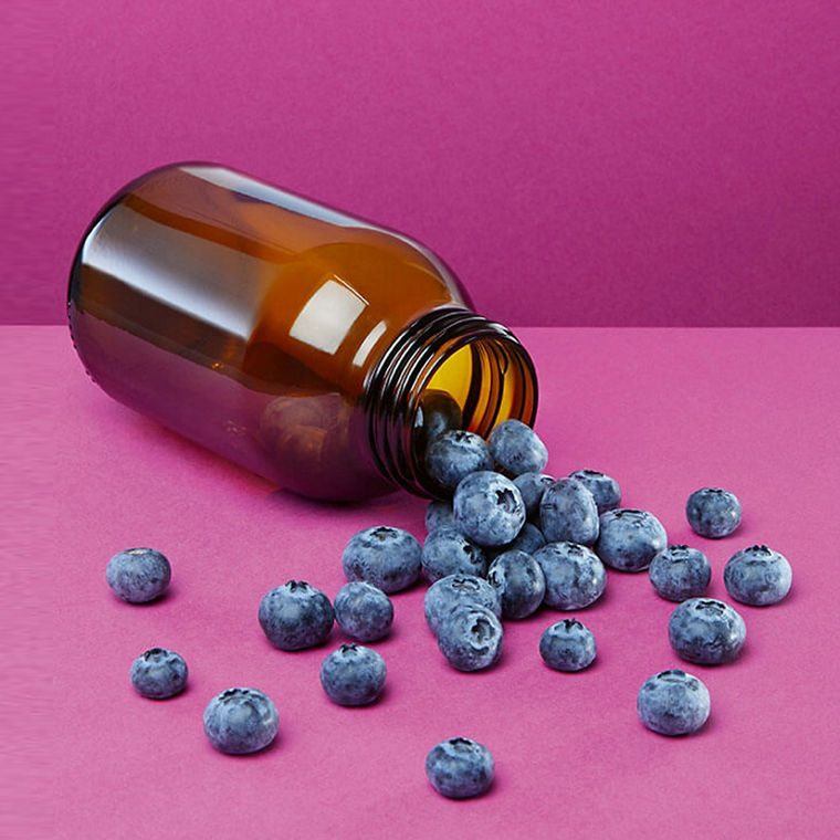 Blaubeeren liegen neben einem umgefallenen braunen Glas