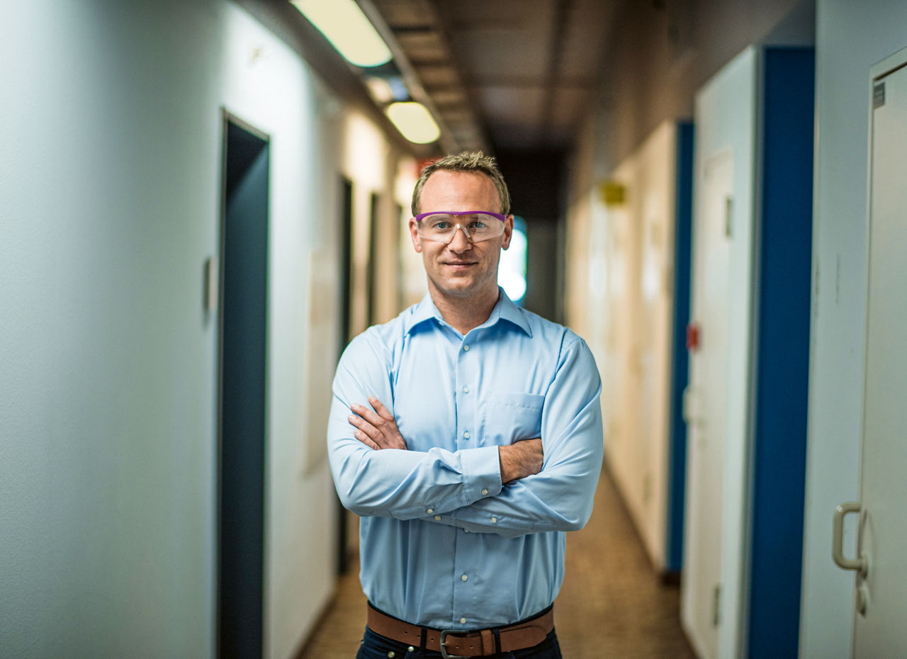 Henning Kemmerer stands with his arms crossed in a long corridor
