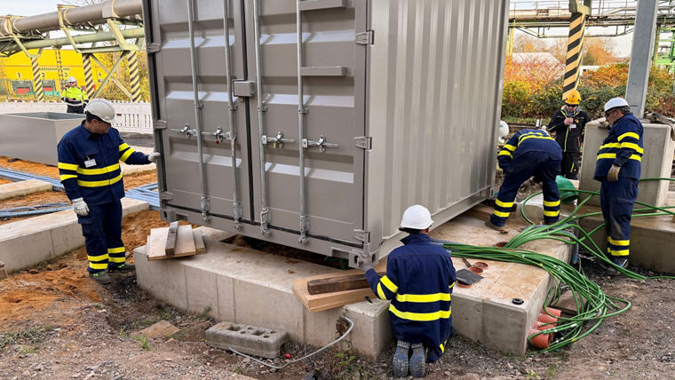 Workers at a grey container