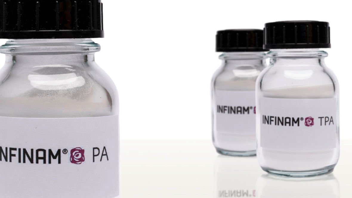 Three glass jars containing INFINAM® Polymer Powders labeled INFINAM® PA and INFINAM® TPA, showcasing high-performance materials for advanced applications in 3D printing and manufacturing.