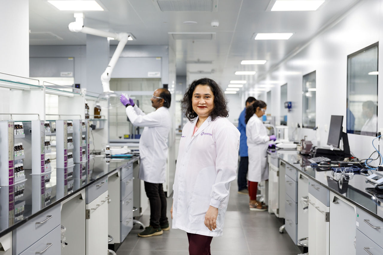 A laboratory scene with professionals in lab coats working at counters filled with equipment and samples.
