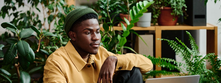 Young black man working with laptop in green officeJunger schwarzer Mann arbeitet mit Laptop in grünem Büro