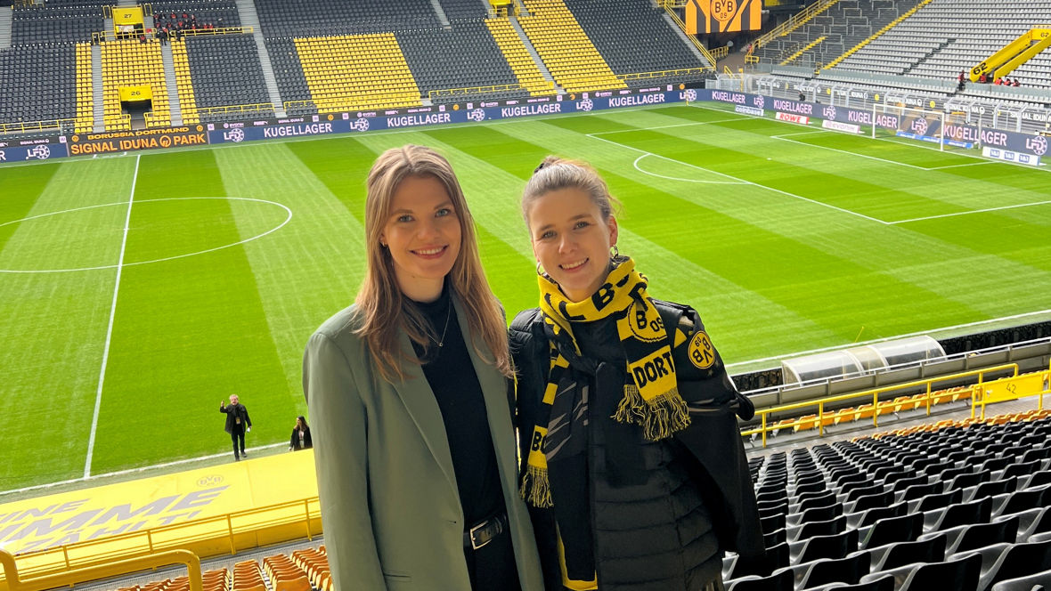 Two women pose in the stands of Signal Iduna Park, home of Borussia Dortmund, before a match.