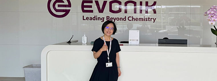 Reception area at Evonik, featuring the logo and a welcoming atmosphere with a staff member.