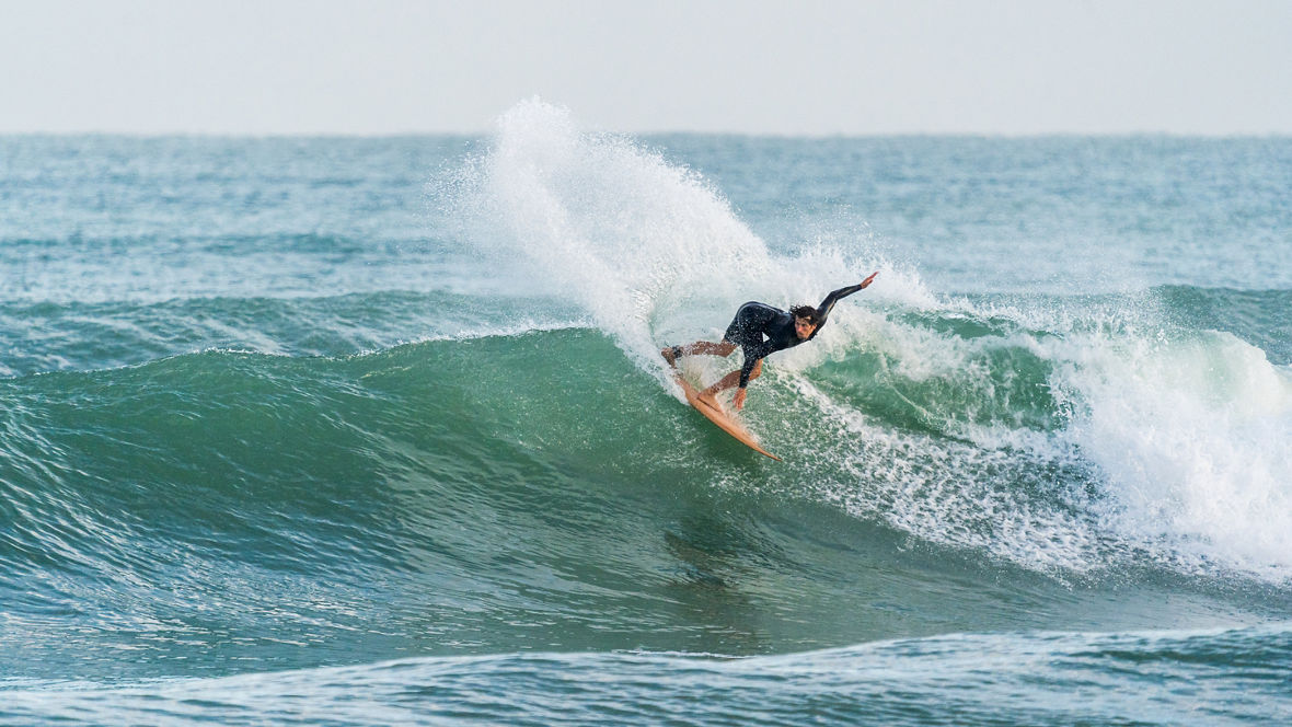 A surfer performs a 180-degree turn on a wave about 3 meters high.