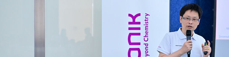 A speaker presents at an Evonik event, with the company logo and tagline displayed prominently.