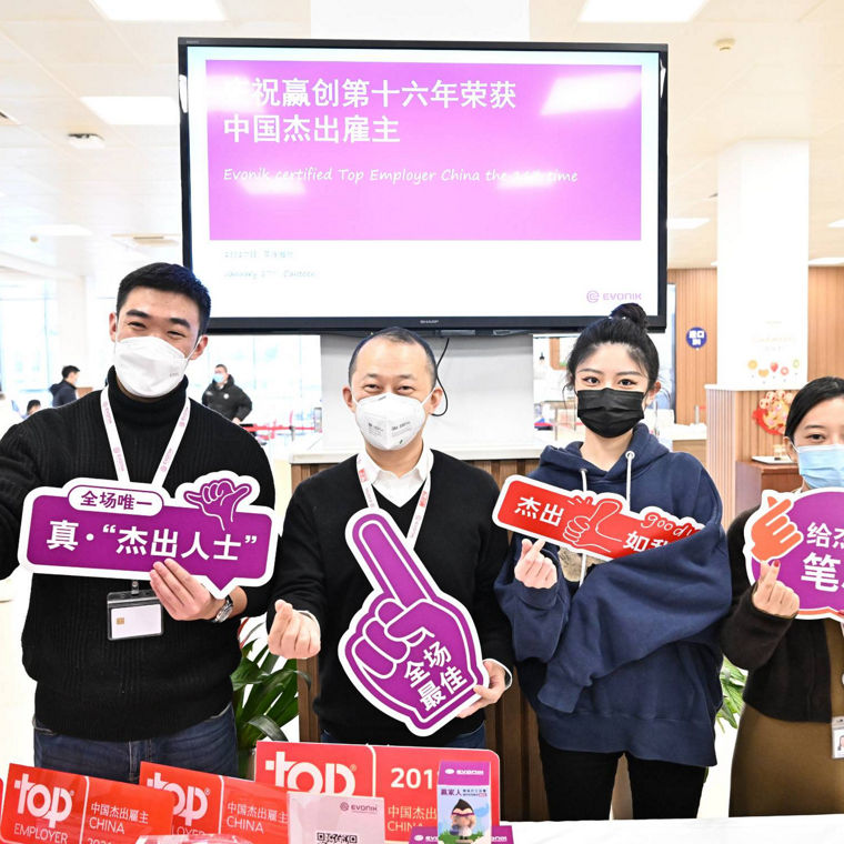 Employees celebrate Evonik's recognition as a Top Employer in China, holding signs promoting the event.