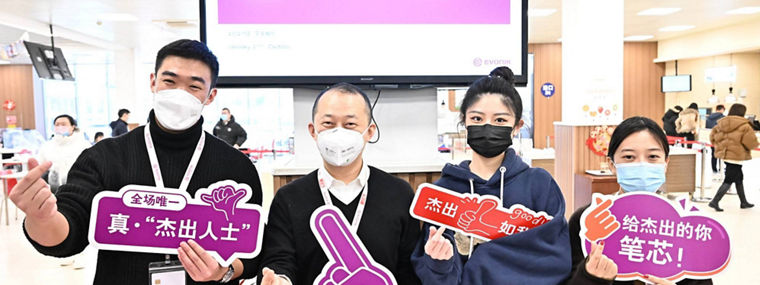 Mitarbeiter von Evonik feiern den Gewinn des Top Employer China Awards mit Schildern und einer Präsentation im Hintergrund.