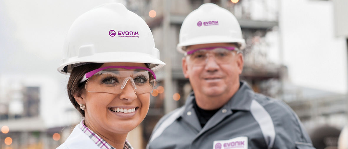 Photo of two Evonik employees with hard hats in front of a plant at the Mobile, Ala., site