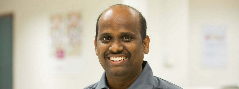 A worker wearing a gray uniform with the Evonik logo, standing in an office environment.