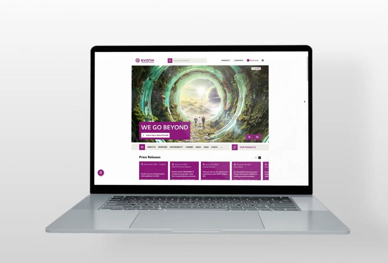 Laptop displaying the Evonik website homepage with a futuristic circular portal illustration.