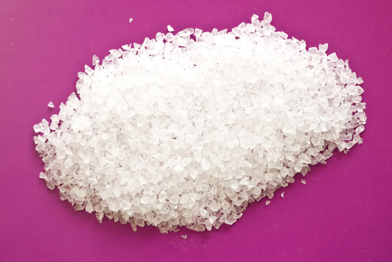 A small pile of white granules on a deep purple surface.