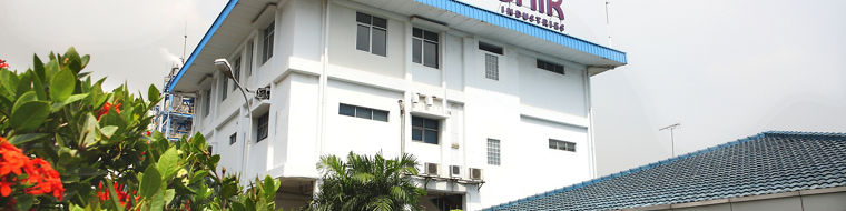 Evonik building with a blue roof and logo, surrounded by well-maintained greenery and flowers.