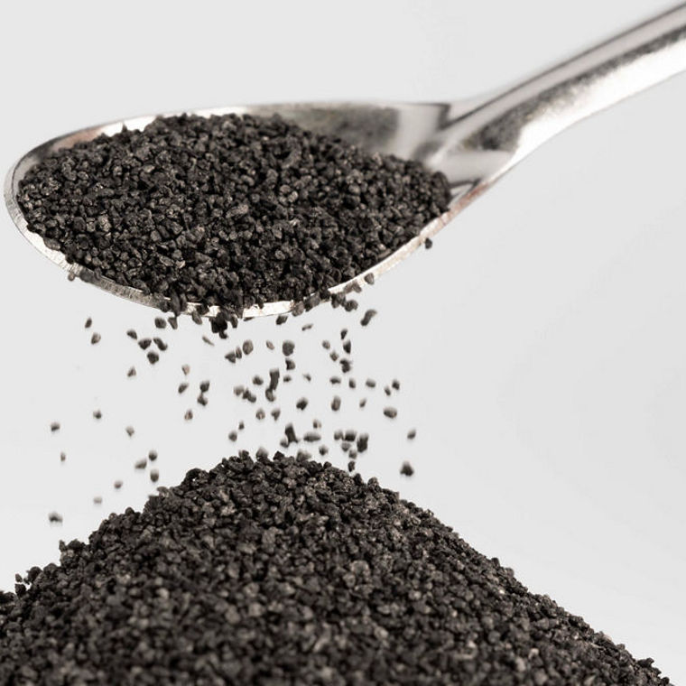 Braune Krümel rieseln von einem Löffel auf einen kleinen Haufen