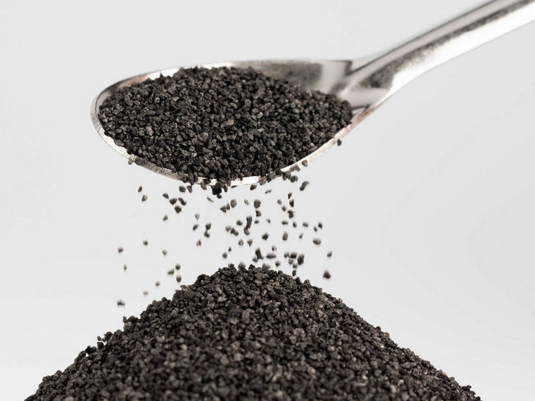 Braune Krümel rieseln von einem Löffel auf einen kleinen Haufen