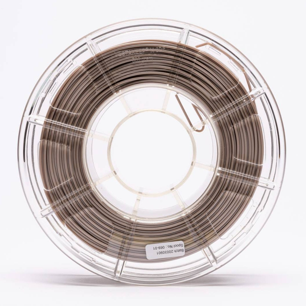 Close-up of a transparent plastic spool containing neatly wound 3D‑printing filament, shown against a light background.
