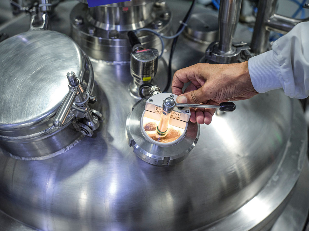 Eine männliche hand gibt etwas Material in einen Mischreaktor.