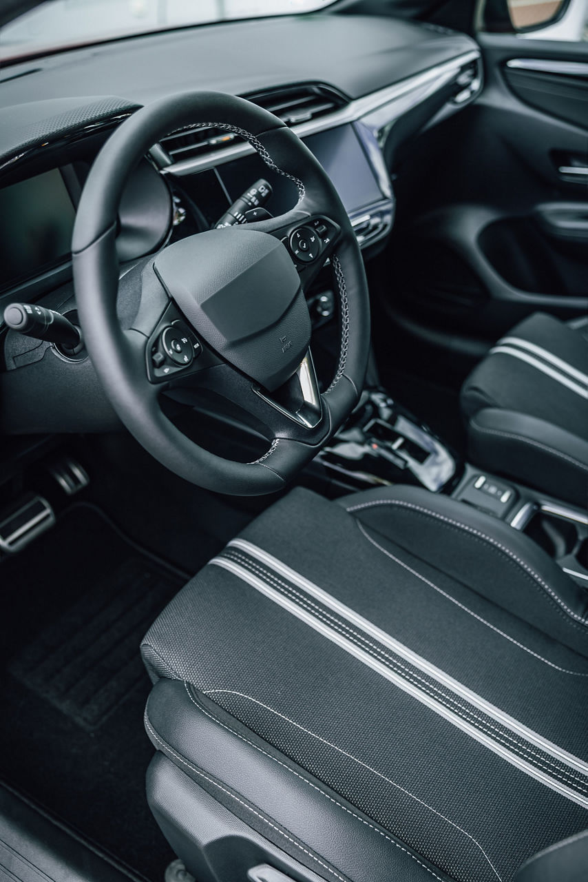 Detailed view of a contemporary vehicle's cabin, showcasing the dashboard, steering wheel, and comfortable fabric seating with accent stripes