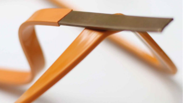 Close-up of a flexible orange plastic strip with a flat metallic tip on a white background.