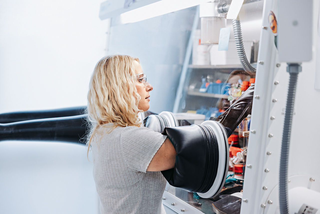 Chemical engineer Lisa Steinwachs puts both arms through a rubber sleeve into an airtight experimental chamber.