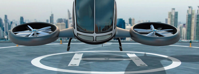 A futuristic white drone with four large rotors hovering above a rooftop helipad in a city.