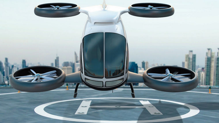 A futuristic white drone with four large rotors hovering above a rooftop helipad in a city.