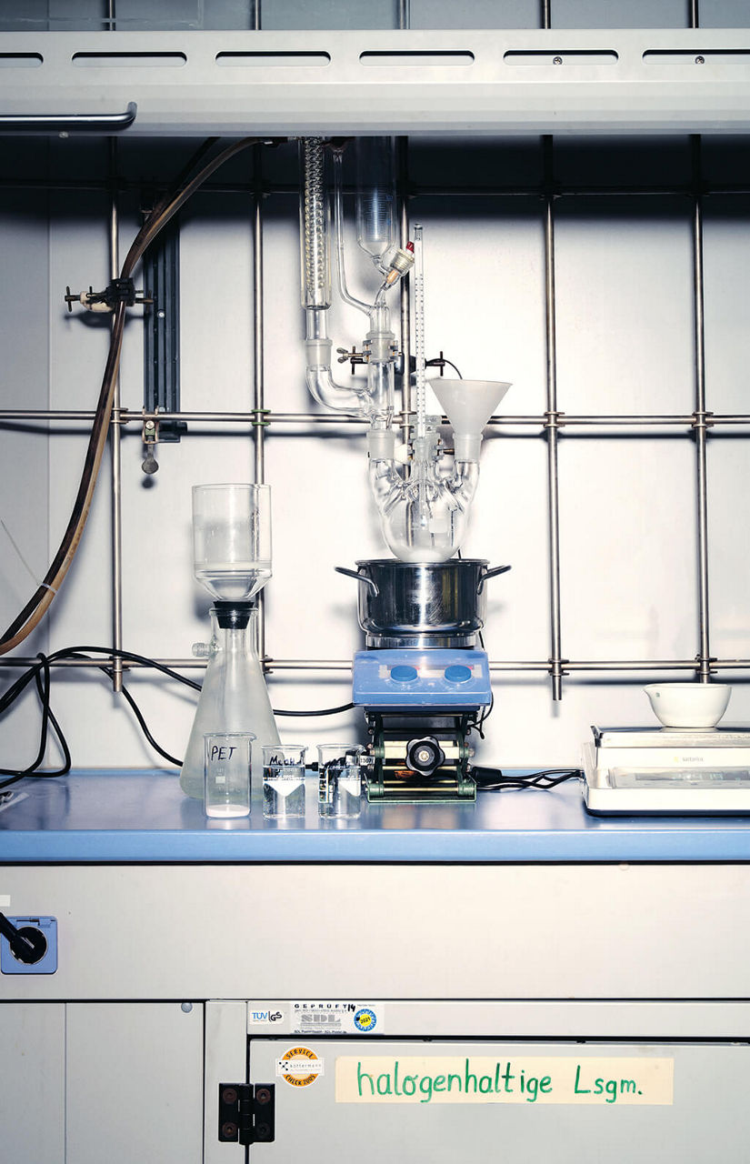 Ein Glaskolben wird im Labor in einem Metalltopf erhitzt.