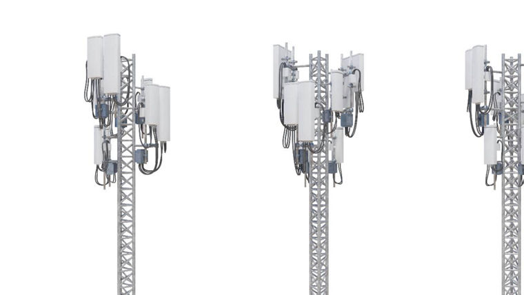 Four cellular network towers with multiple white antennas and black cables on metal lattice structures.
