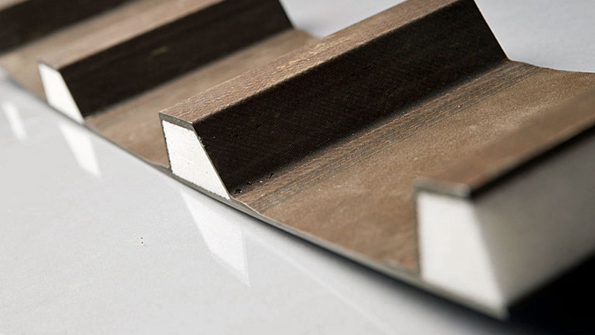 Close-up of a brown corrugated material with a white foam core on a reflective surface.