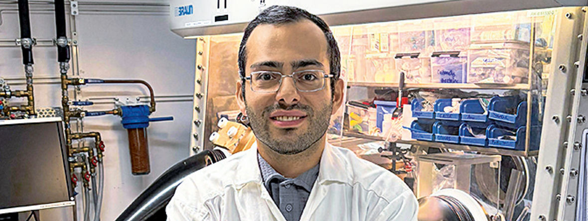 Saeed Mardi steht mit verschränkten Armen, Laborkittel, Handschuhen und Schutzbrille in einem Chemielabor.
