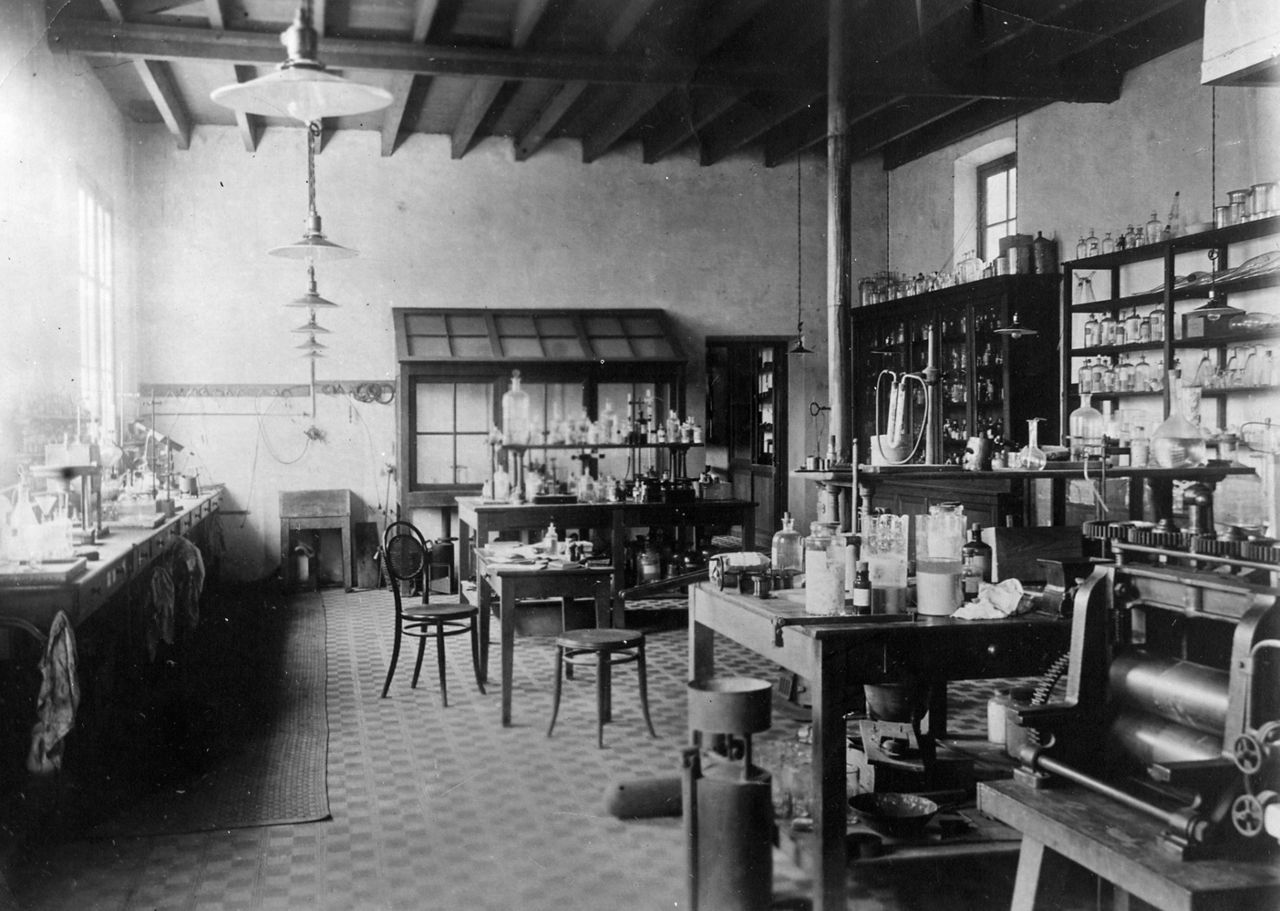 Blick in ein Labor mit hohen Fenstern, zahlreichen Gefäßen und einer Presse