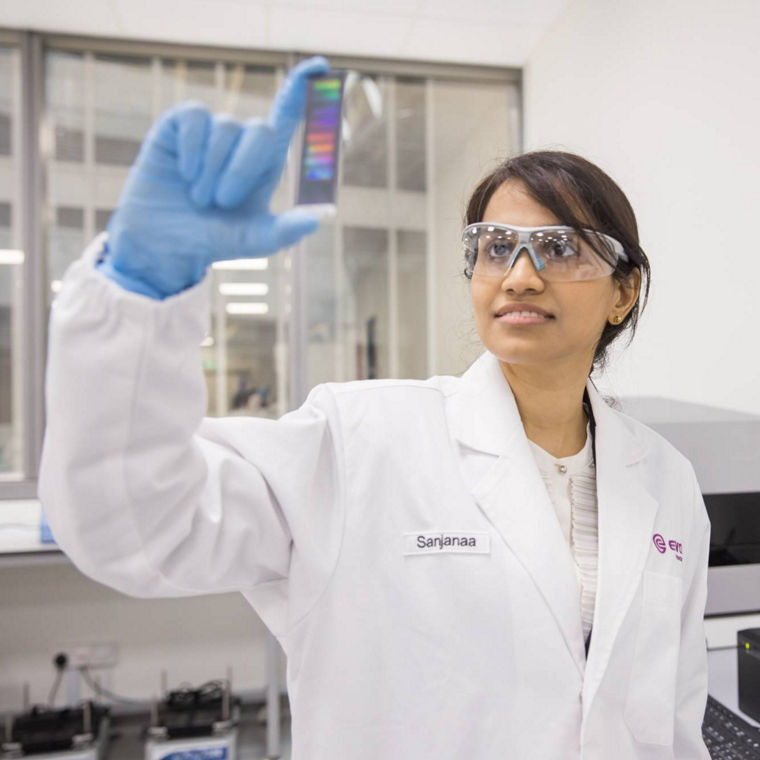 A lab technician in a white coat holds a colorful gel, analyzing results in a modern laboratory setting.