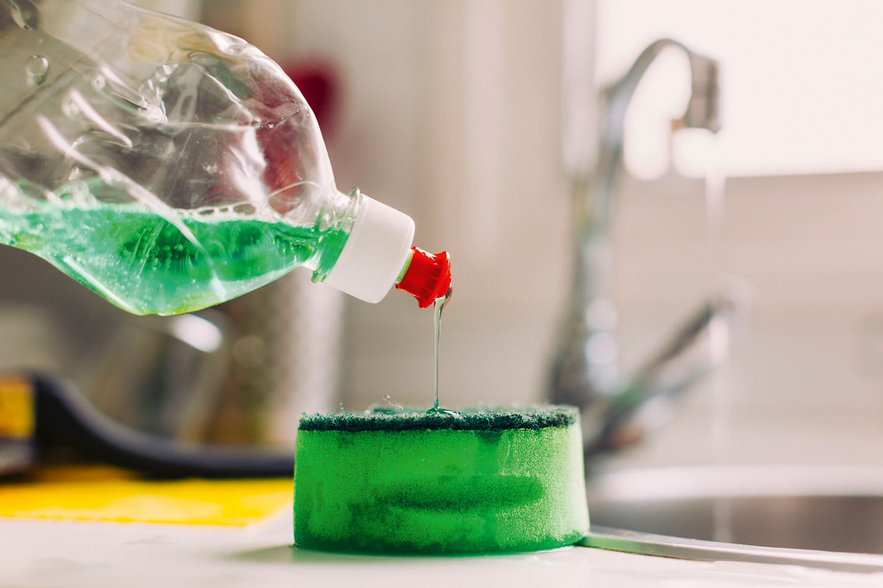 Ein Handspülmittel wird aus einer Spülmittelflasche auf einen Schwamm gegeben.